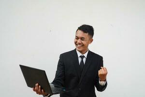 Portrait Young Asian businessman happy with smiling face read good news, finger pointing laptop isolated on white background photo