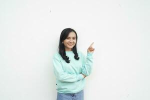 Portrait Indonesian beautiful woman wearing light blue sweater smile dan happy gesture finger pointing to white background photo