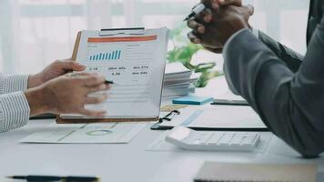 grupp av självsäker företag människor punkt till grafer och diagram till analysera marknadsföra data, balans ark, konto, netto vinst till planen ny försäljning strategier till öka produktion kapacitet. video