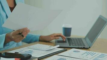 Asian Business woman using calculator and laptop for doing math finance on an office desk, tax, report, accounting, statistics, and analytical research concept video