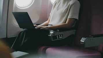 mujer utilizando ordenador portátil mientras es sentado en avión cerca ventana. video