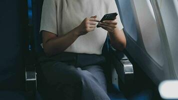 in viaggio e tecnologia. volante a primo classe. bella giovane imprenditori donna utilizzando smartphone mentre seduta nel aereo. video