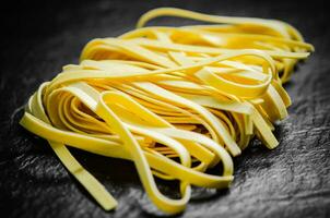 Homemade pasta tagliatelle. On black table. photo