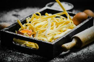 Homemade pasta tagliatelle. On black table. photo