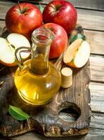 Apple cider vinegar with fresh red apples on a cutting Board. photo