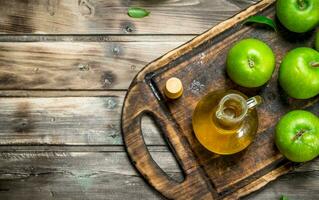 Apple cider vinegar with green apples on an old Board. photo