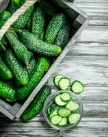 Cucumbers in the box and cucumber slices in the bowl. photo