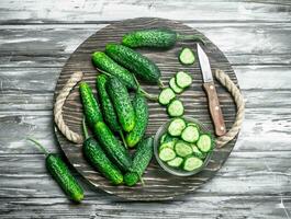 Pieces of cucumbers in a bowl on a cutting Board with a knife. photo