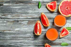 Grapefruit juice in a glass and pieces of fresh grapefruit. photo