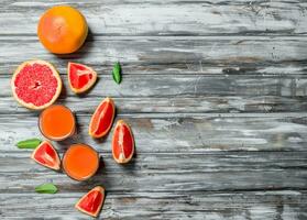 Grapefruit juice in a glass and pieces of fresh grapefruit. photo