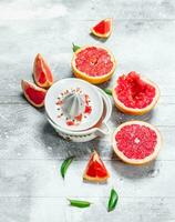 The slices of fresh grapefruit and a juicer. photo