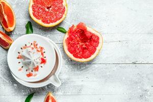 The slices of fresh grapefruit and a juicer. photo