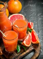 Juice of ripe grapefruit in a jug on a cutting Board. photo