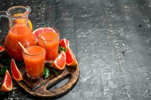 Juice of ripe grapefruit in a jug on a cutting Board. photo