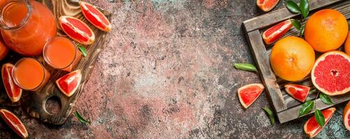 jugo en un lanzador y piezas de pomelo en un corte tablero. foto