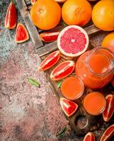 Juice in a pitcher and pieces of grapefruit on a cutting Board. photo