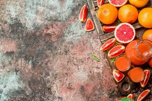 Juice in a pitcher and pieces of grapefruit on a cutting Board. photo