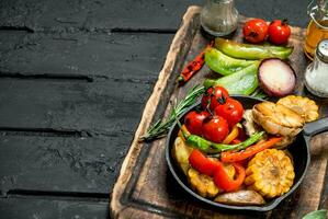 Various grilled vegetables in a pan with spices on a wooden Board. photo