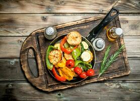 Assortment of grilled vegetables with a pan of herbs and spices on a cutting Board. photo
