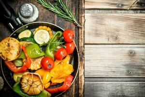 Assortment of grilled vegetables with a pan of herbs and spices on a cutting Board. photo