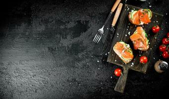 Sandwich with pieces of salmon on a cutting board. photo