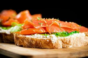 Sandwich with pieces of salmon on a cutting board. photo