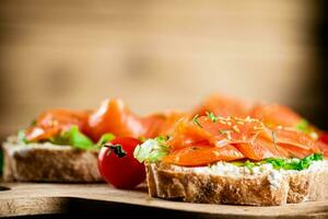 Sandwich with salmon on a wooden background. photo