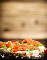 Sandwich with salmon on a wooden background. photo