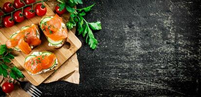 Salmon sandwich on a cutting board with herbs and tomatoes. photo