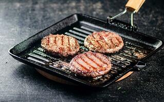 Cooking a delicious grilled burger on a pan with oil bubbles. photo