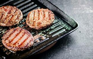 Cooking a delicious grilled burger on a pan with oil bubbles. photo