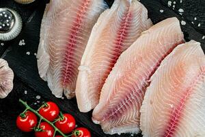 Raw fish fillet with spices and tomatoes on a stone board. photo