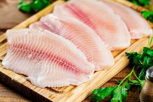 Raw fish fillet with parsley on a cutting board. photo