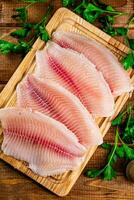 Raw fish fillet with parsley on a cutting board. photo