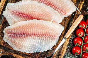 Raw fish fillet with tomatoes and herbs. photo