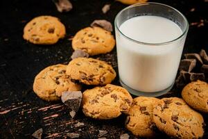 Homemade cookies with pieces of milk chocolate and a glass of milk. photo