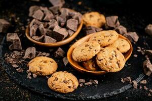 Cookies with pieces of milk chocolate on a stone board. photo