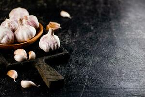 Garlic on a wooden plate on a cutting board. photo