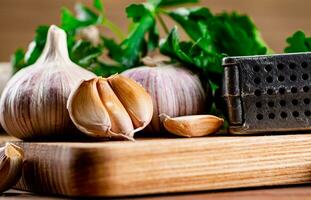 Garlic with parsley on a wooden cutting board. photo