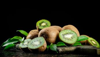 A pile of kiwi with leaves on a cutting board. photo