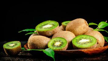 Fresh kiwi with leaves on a wooden plate. photo