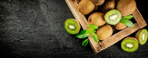 Ripe kiwi with leaves on a wooden tray. photo