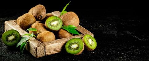 Ripe kiwi with leaves on a wooden tray. photo