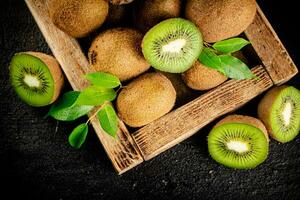 Ripe kiwi with leaves on a wooden tray. photo