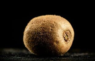 One ripe unpeeled kiwi on the table. photo