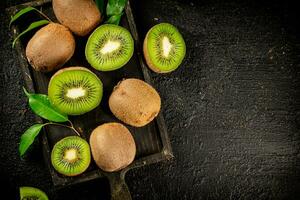 Pieces of kiwi with leaves on a cutting board. photo
