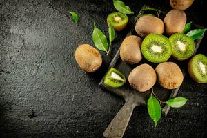 Pieces of kiwi with leaves on a cutting board. photo