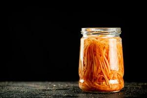 A glass jar with canned carrots. photo
