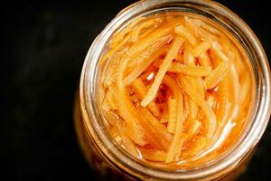 A glass jar with canned carrots. photo