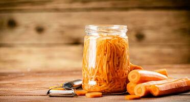 Canned carrots in a glass jar on the table. photo